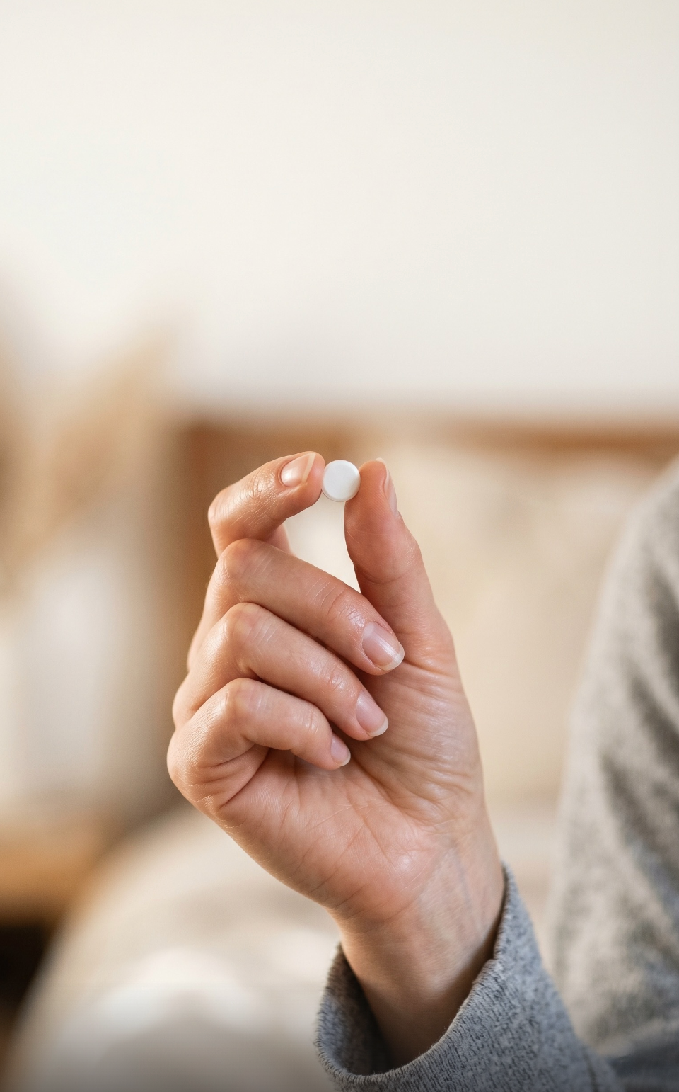 Hand holding a single white oral treatment tablet