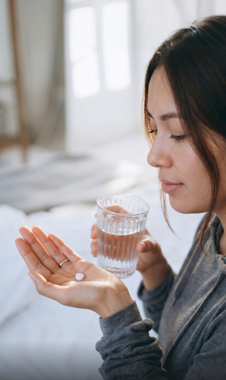 Woman taking her daily oral weight loss tablet with a glass of water