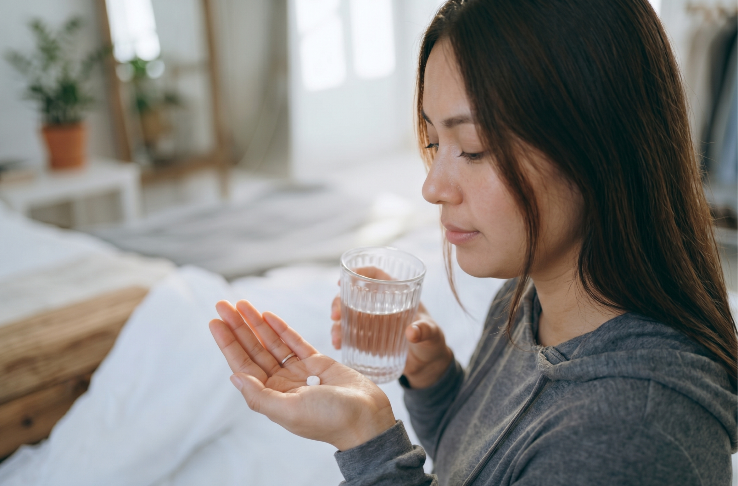Woman holding a tablet and a glass of water in her bedroom